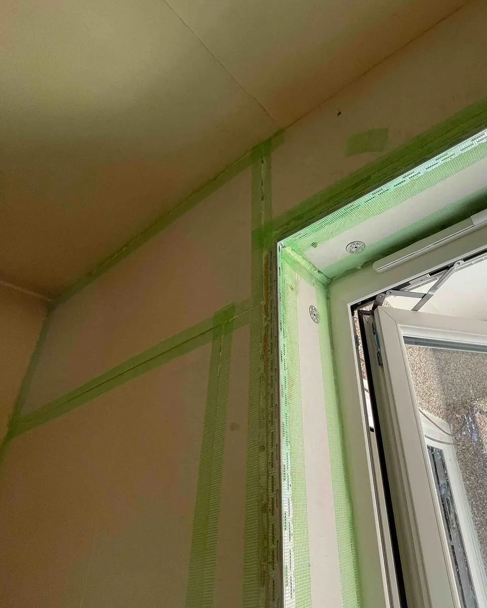 Close up of a window reveal lined with insulation and finished with a metal bead and scrim tape