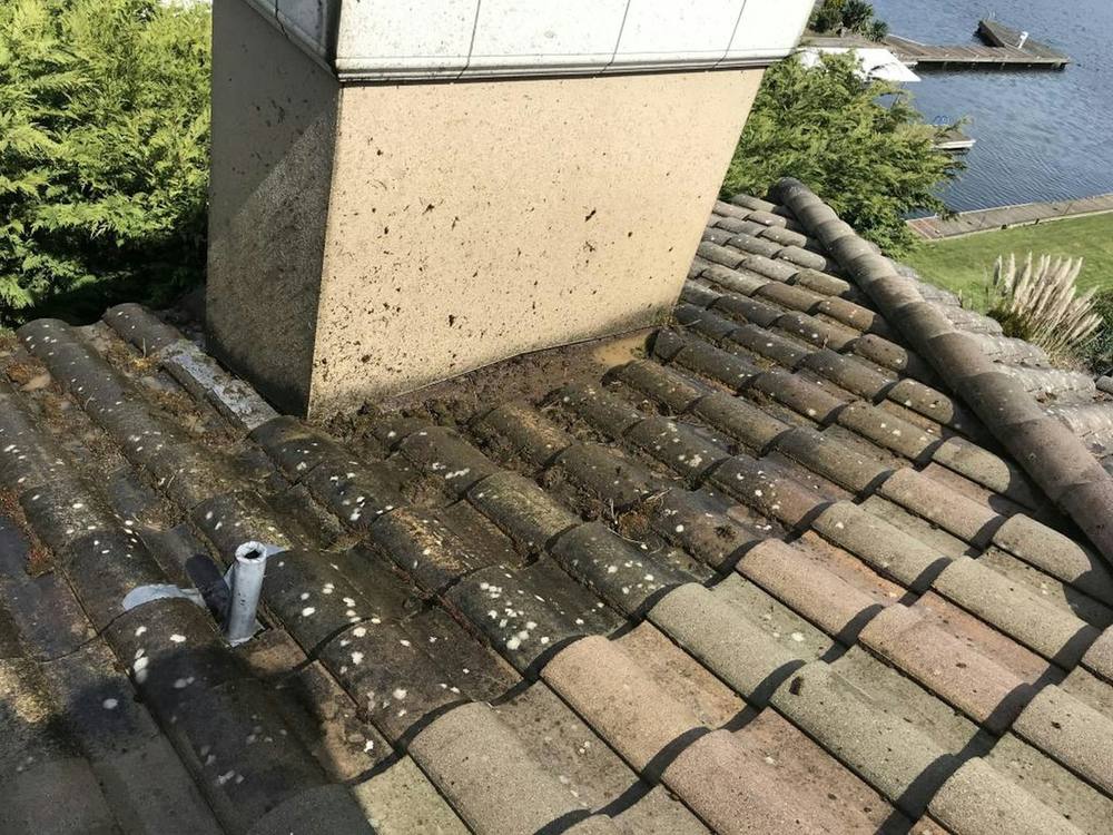 A chimney stack rising through a weathered tiled roof