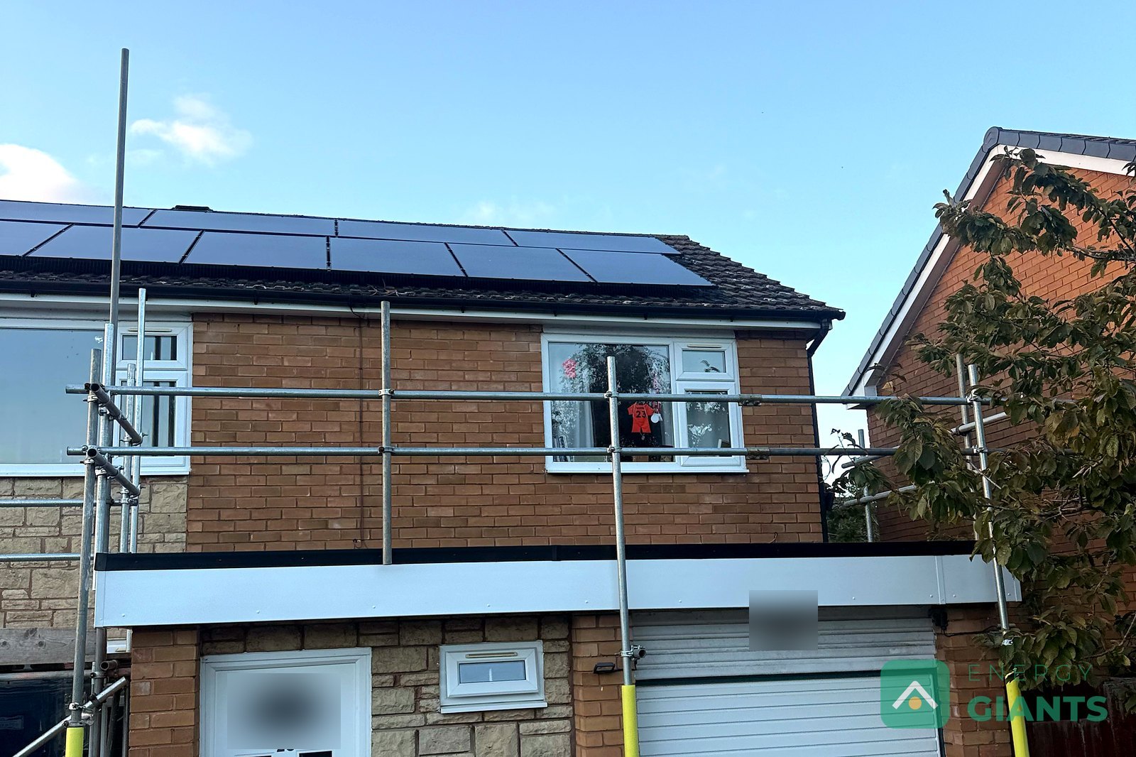 A brick semi detached house with its garage flat roof newly finished in black EPDM and white fascias