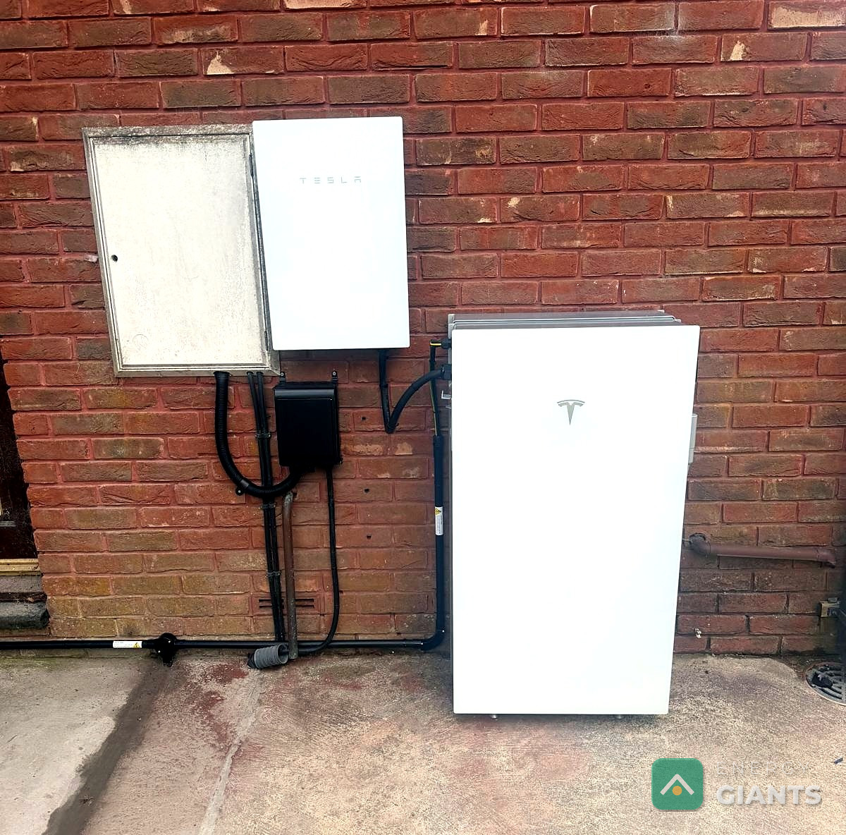 Tesla Powerwall 3 on the outside brick wall of a house near Aberystwyth with its isolator alongside, installed by Energy Giants