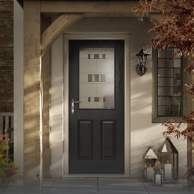 A dark composite door in a stone porch lit by lanterns