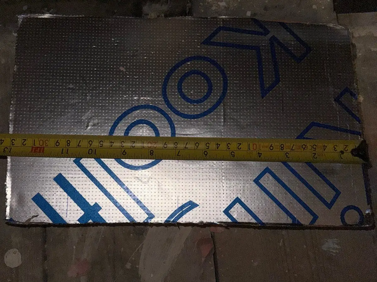 An offcut of Kooltherm board with its printed foil facing, measured with a tape