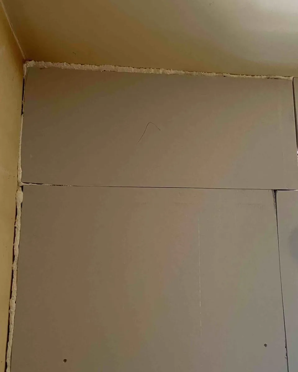Kooltherm K118 boards freshly fixed to a bedroom wall, with the perimeter gaps filled with foam