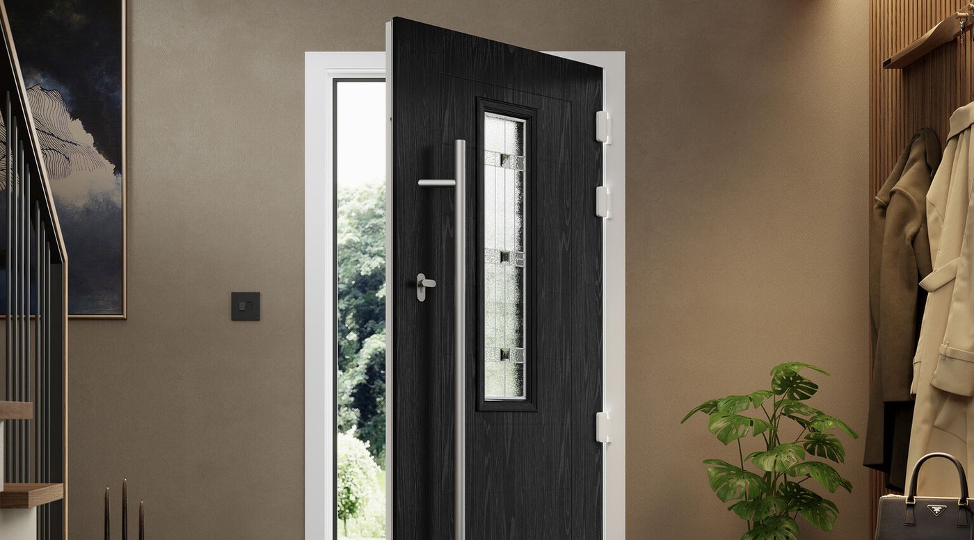 An open black composite door with a long steel handle in a modern hallway